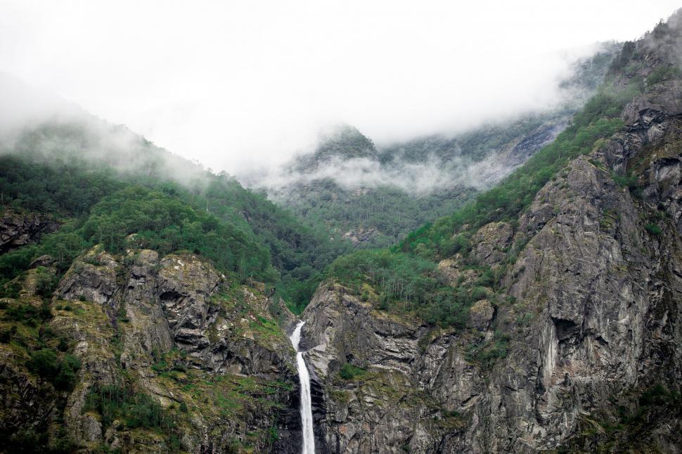 Free Image of Majestic Waterfall Amid Mountain Range 