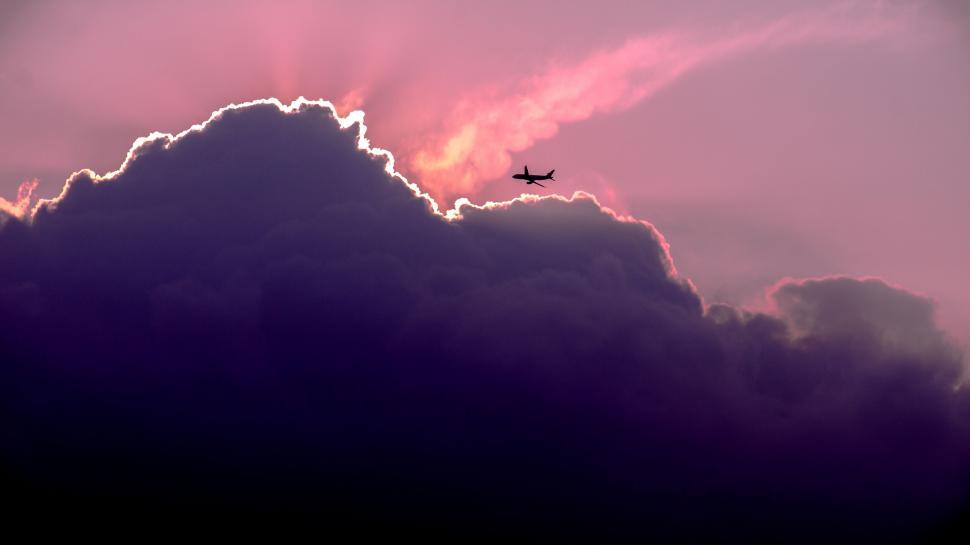 Free Image of A Plane Flying Through a Cloudy Sky at Sunset 