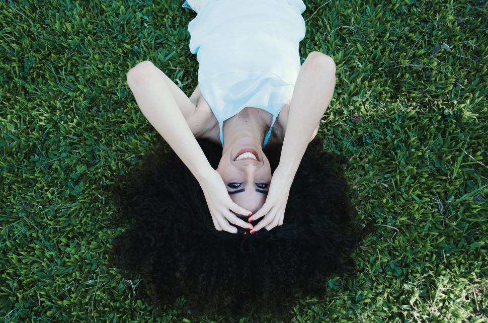 Free Image of Woman Laying on Lush Green Field 