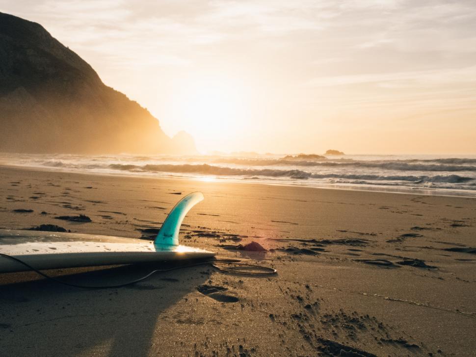 Free Image of Surfboard Resting on Beach at Sunset 
