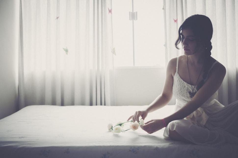 Free Image of Woman Sitting on Bed Next to Window 