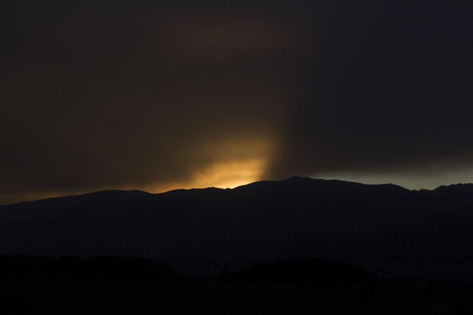 Free Image of Sun Shining Through Clouds Over Mountains 