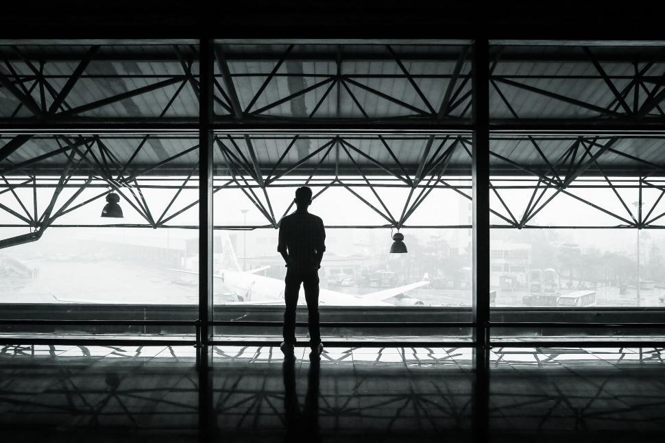 Free Image of Man Standing in Front of Large Window 