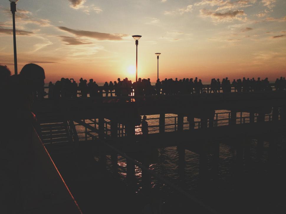 Free Image of Group of People Standing on Pier at Sunset 