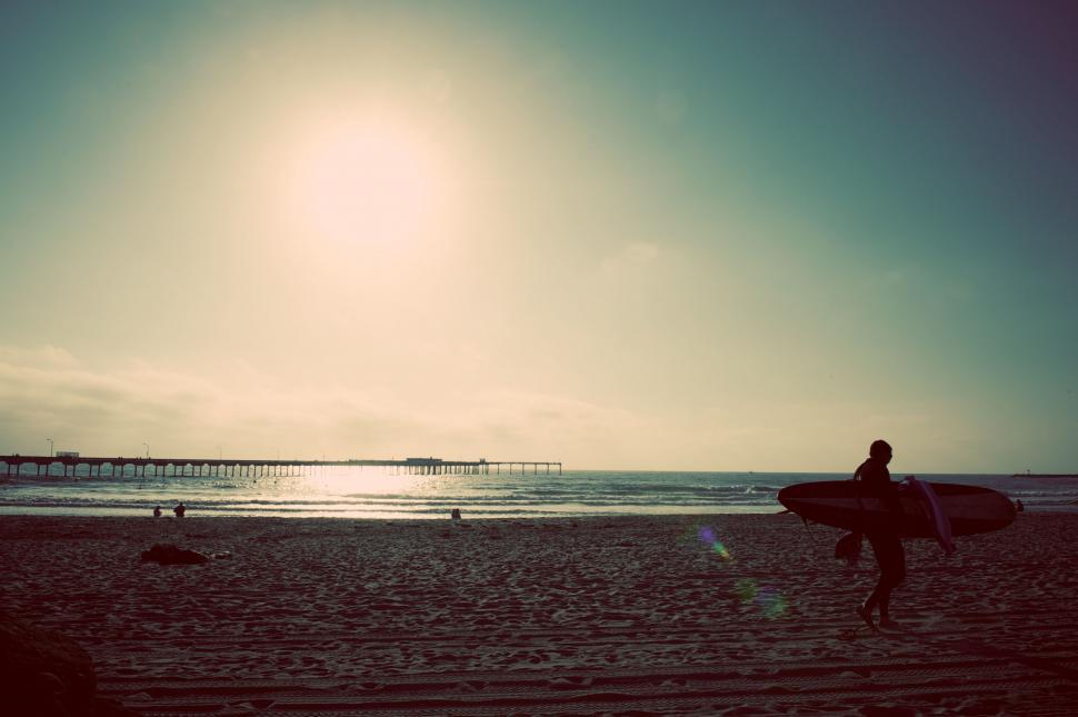 Free Image of Man Holding Surfboard on Sandy Beach 