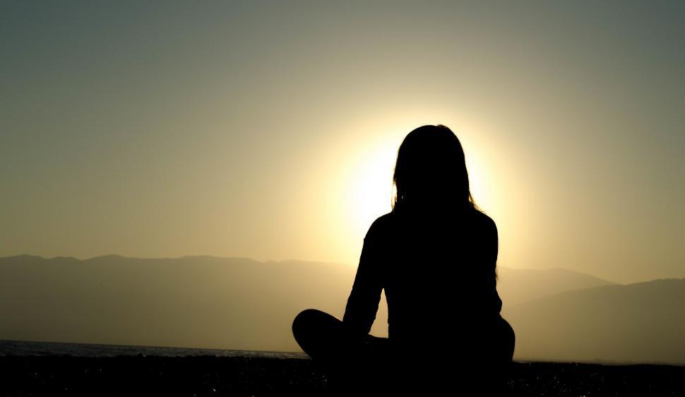 Free Image of Person Sitting Silhouetted Against Sun 