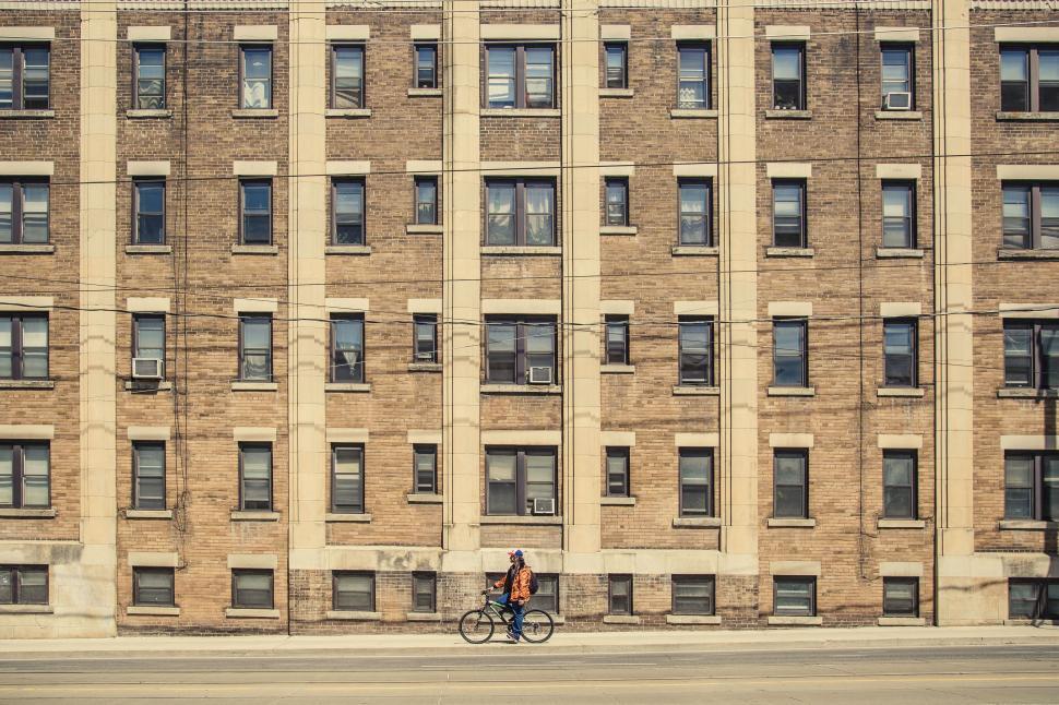 Free Image of Person Riding Bike in Front of Tall Building 