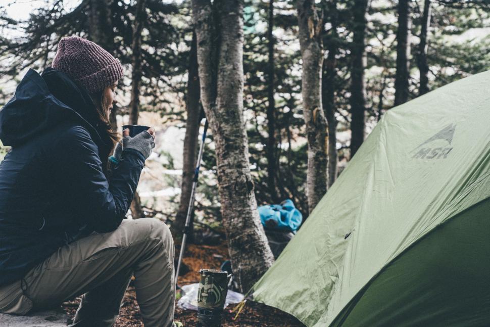 Free Image of Man Sitting Next to Tent in the Woods 