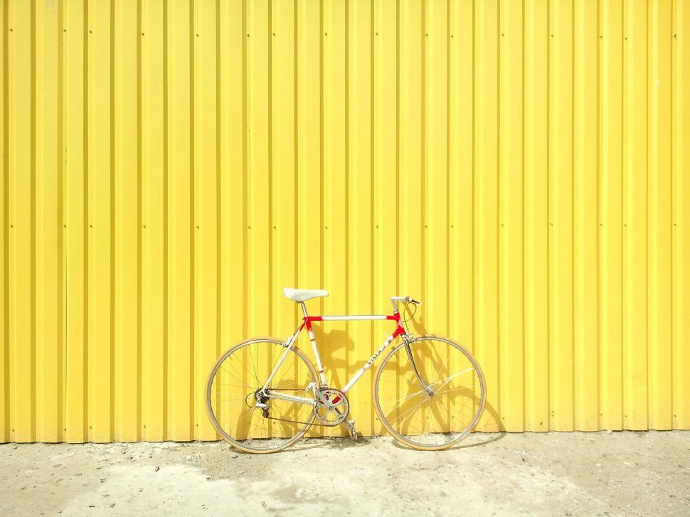 Free Image of White Bicycle Parked in Front of Yellow Wall 