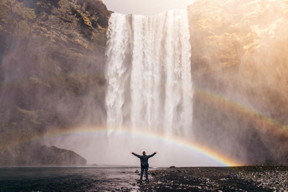 Free Image of Person Standing in Front of Waterfall With Rainbow 