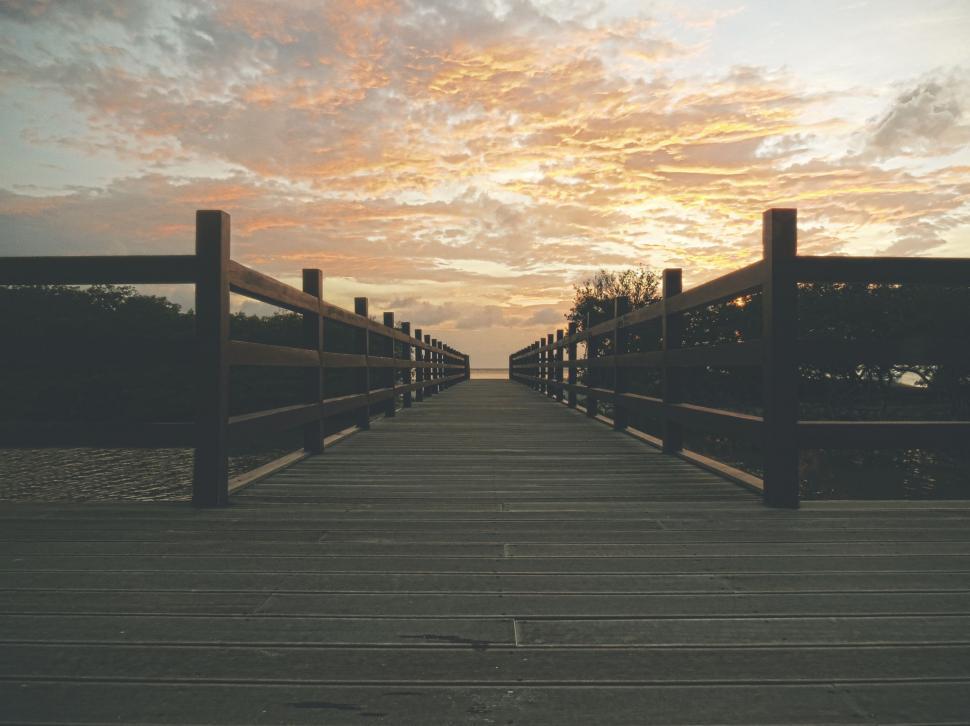 Free Image of Wooden Walkway Leading to a Body of Water 