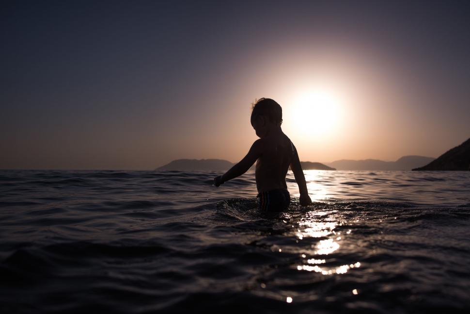 Free Image of Person Standing in Water at Sunset 