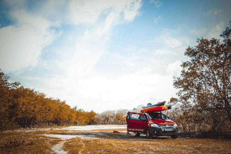 Free Image of Car With Kayak on Top Parked on Dirt Road 
