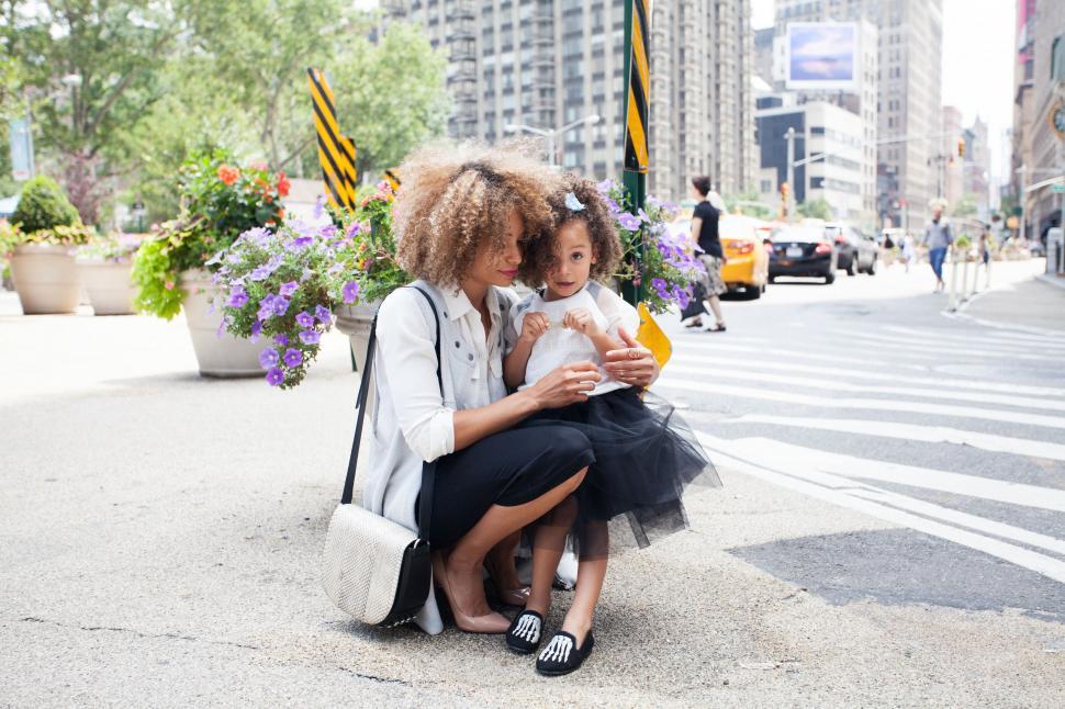Free Image of Mother and Daughter Sitting on Curb Looking at Cell Phone 