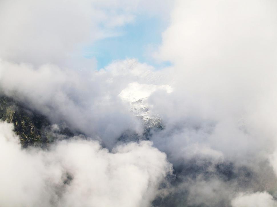 Free Image of Mountain Covered in White Clouds Under Blue Sky 