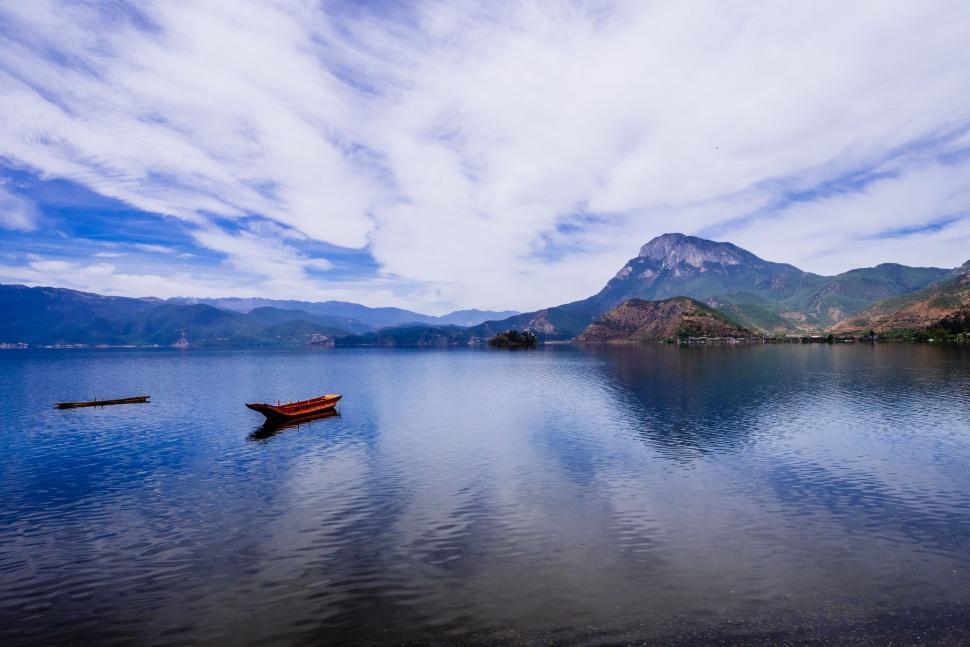 Free Image of Boat Floating on Lake Surrounded by Mountains 