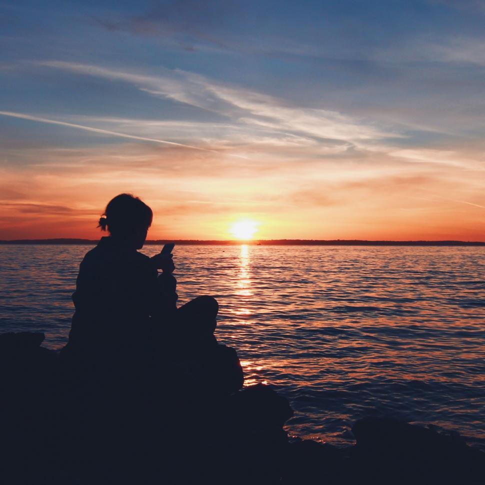 Free Image of Person Sitting on Rock Watching Sunset 
