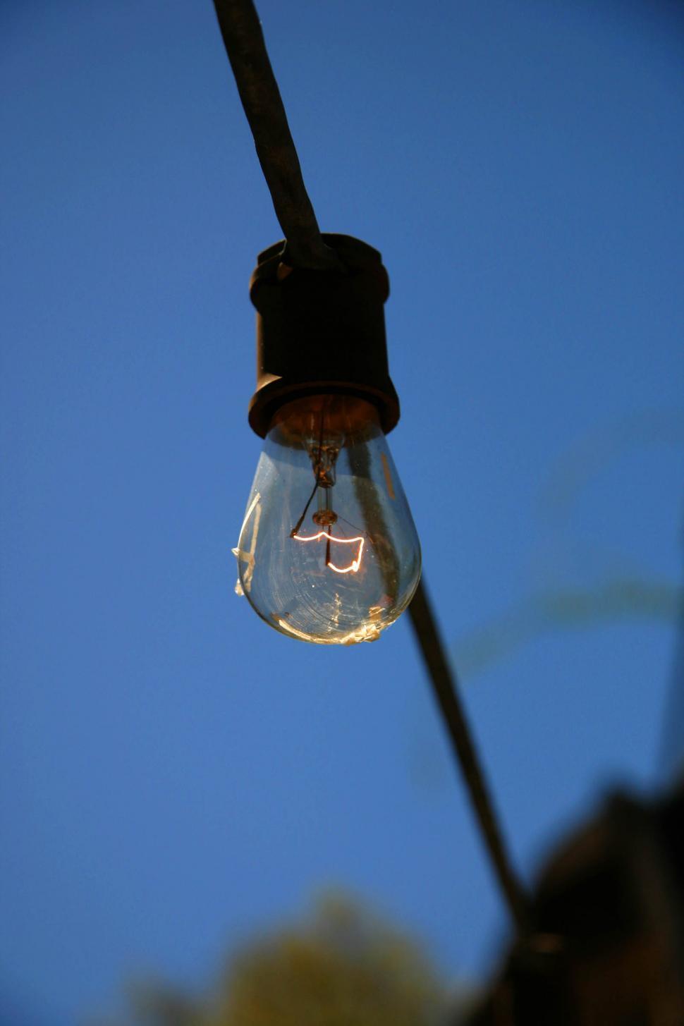 Free Image of Hanging Light Bulb With Blue Sky Background 