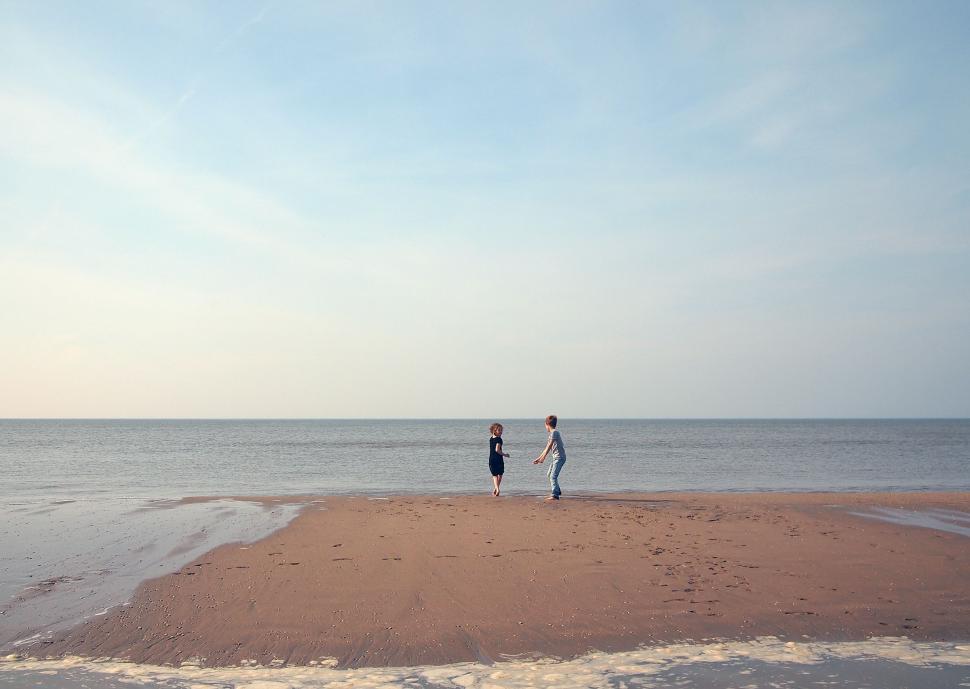 Free Image of Couple Standing on Sandy Beach 