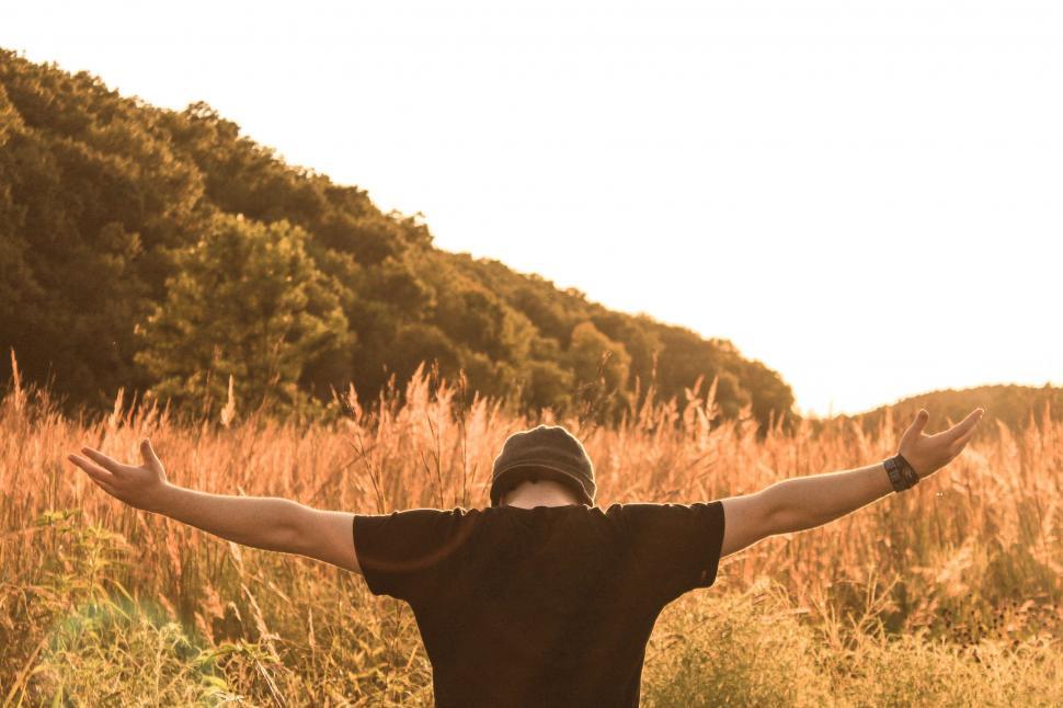 Free Image of Man Standing in Field With Outstretched Arms 