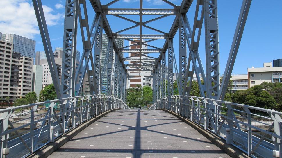 Free Image of Large Metal Bridge Over River With City Buildings in Background 