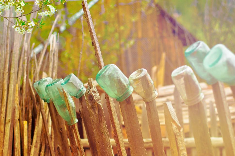 Free Image of Row of Wooden Fence Posts With Green Glass Bottles 