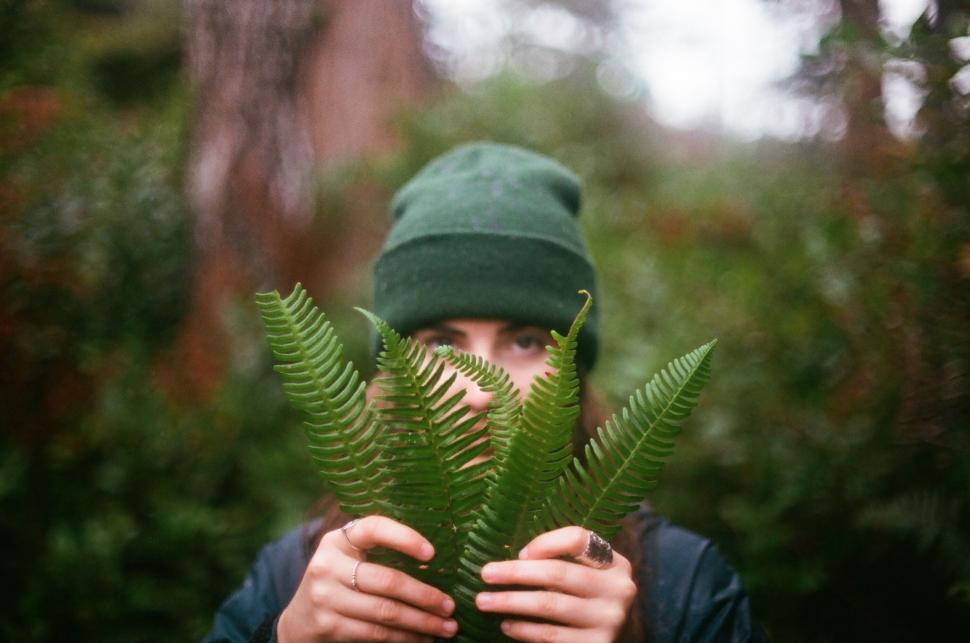 Free Image of Person Wearing Green Hat Holding Plant 