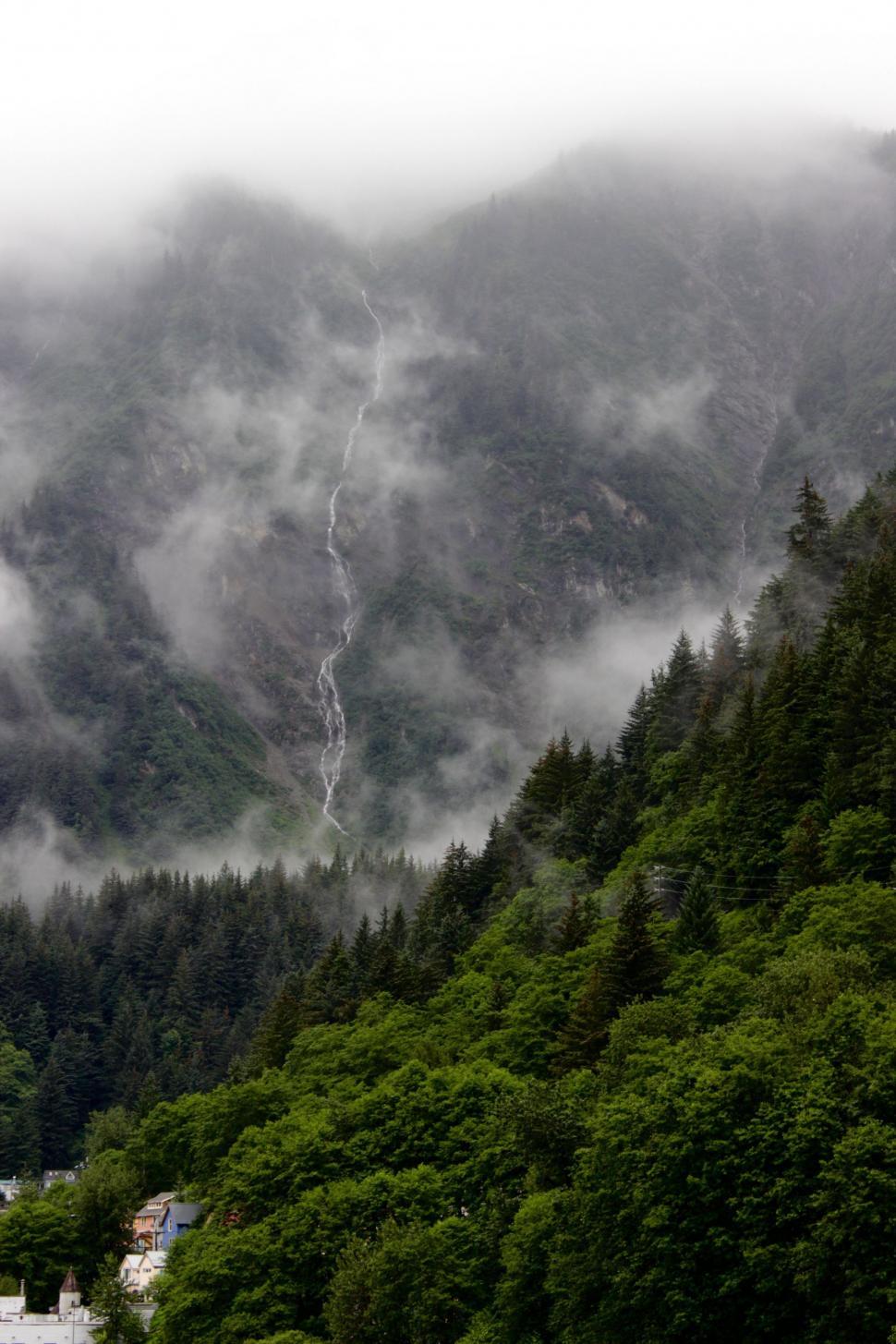 Free Image of Mountain Covered in Clouds and Trees Next to River 