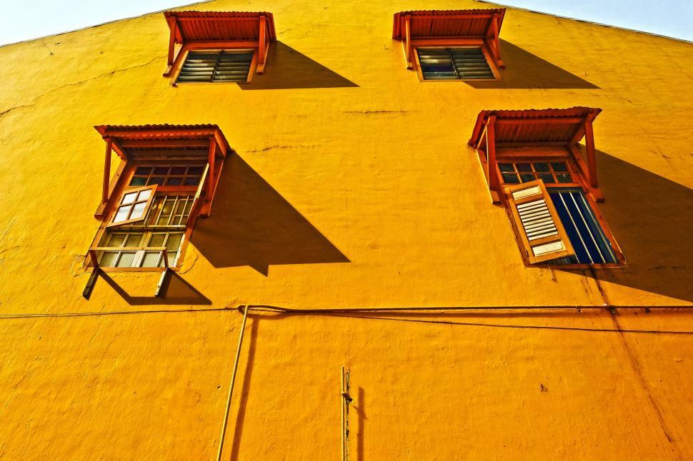 Free Image of Yellow Building With Four Windows and Shutters 