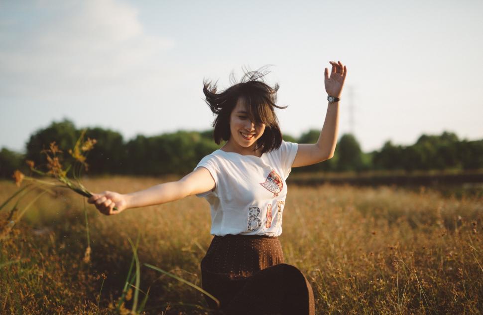 Free Image of Woman Standing in Field With Arms Outstretched 