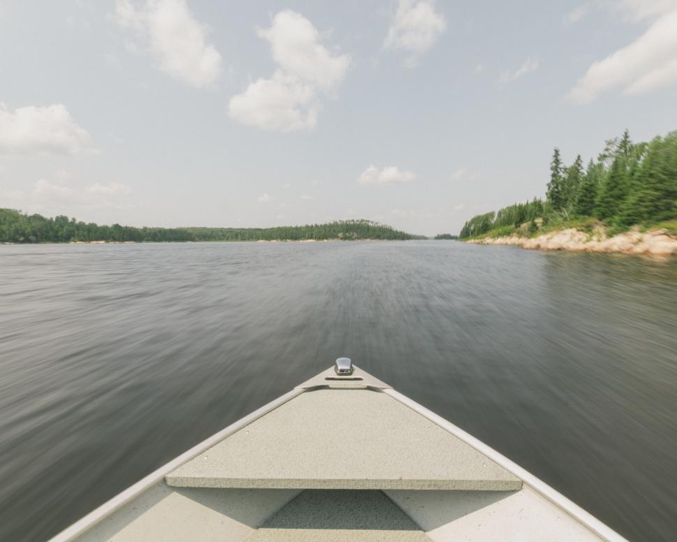 Free Image of Boat Traveling Down River Next to Forest 