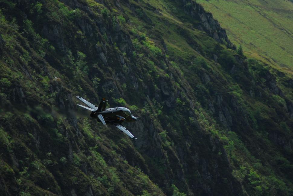 Free Image of Small Plane Flying Over Lush Green Hillside 