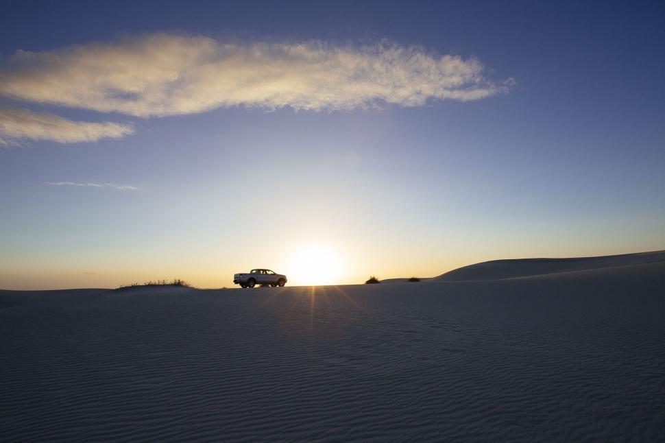 Free Image of Car Driving Through Desert at Sunset 