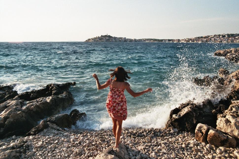 Free Image of Woman Standing on Rocky Beach by the Ocean 