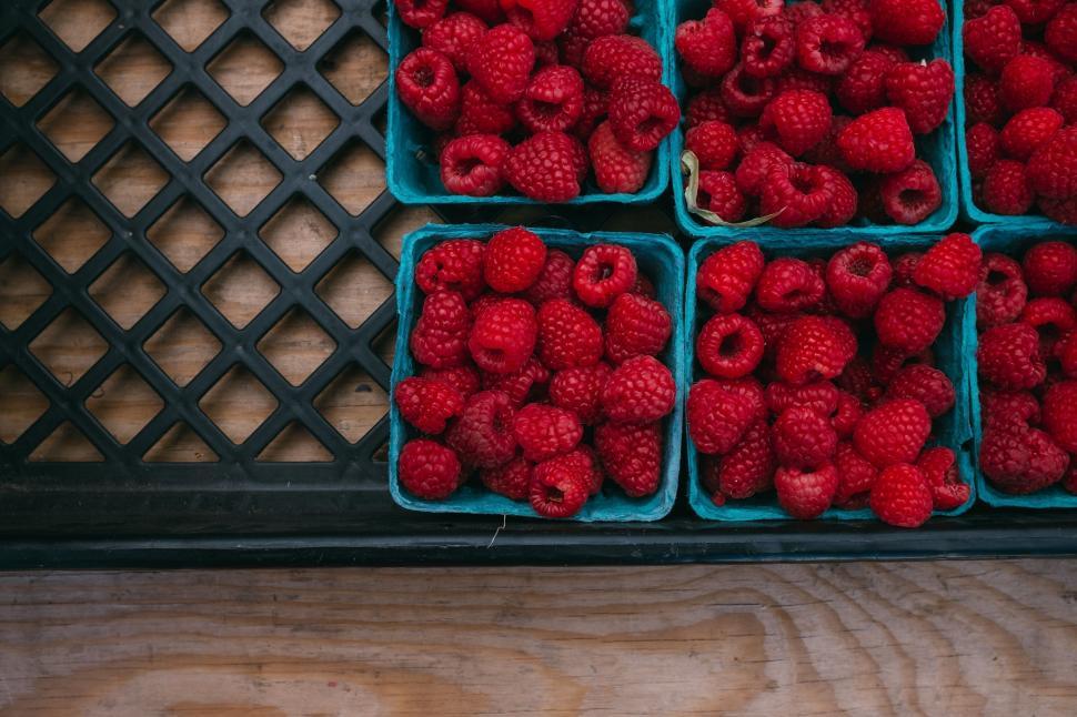 Free Image of Fresh Raspberries in Blue Plastic Containers on Wooden Table 