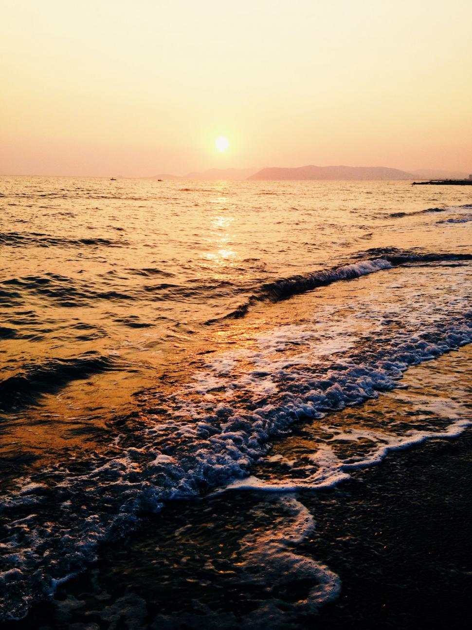 Free Image of Sun Setting Over Water at the Beach 
