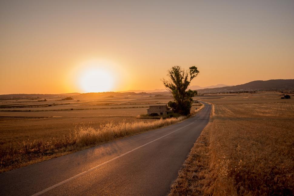 Free Image of The Sun Sets Over a Rural Road 