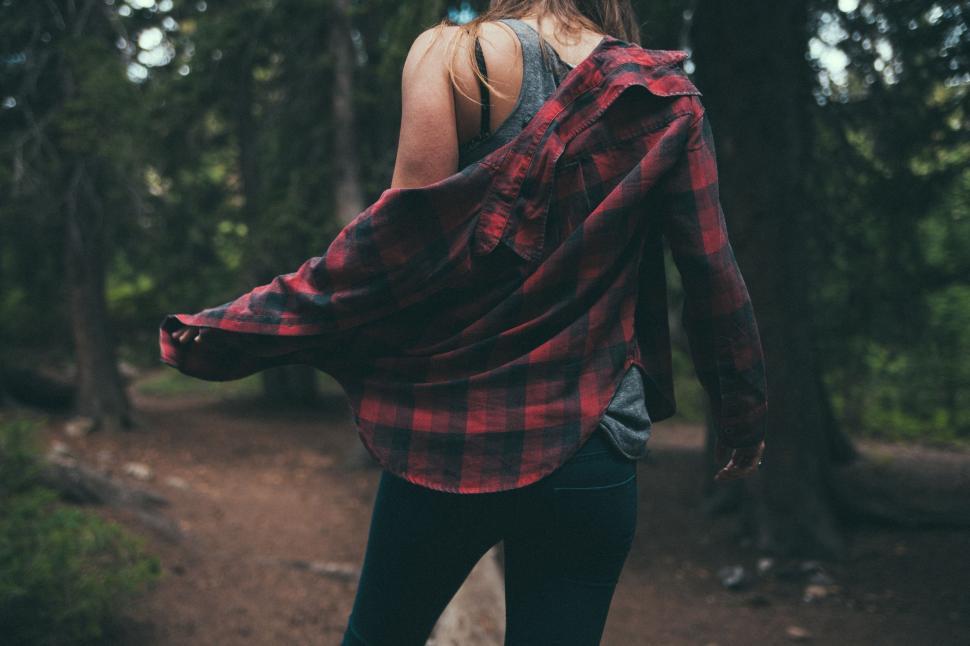 Free Image of Woman Walking Through Woods in Red and Black Plaid Shirt 
