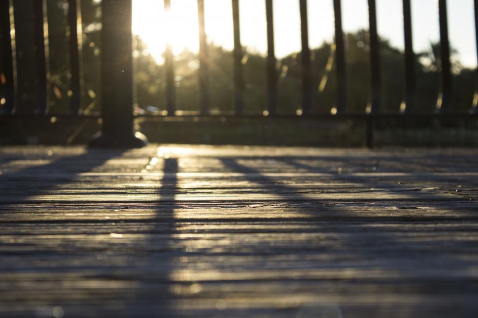 Free Image of Sun Setting Behind Fence and Bench 