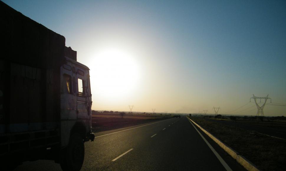 Free Image of Truck Driving Down Highway With Sun in Background 