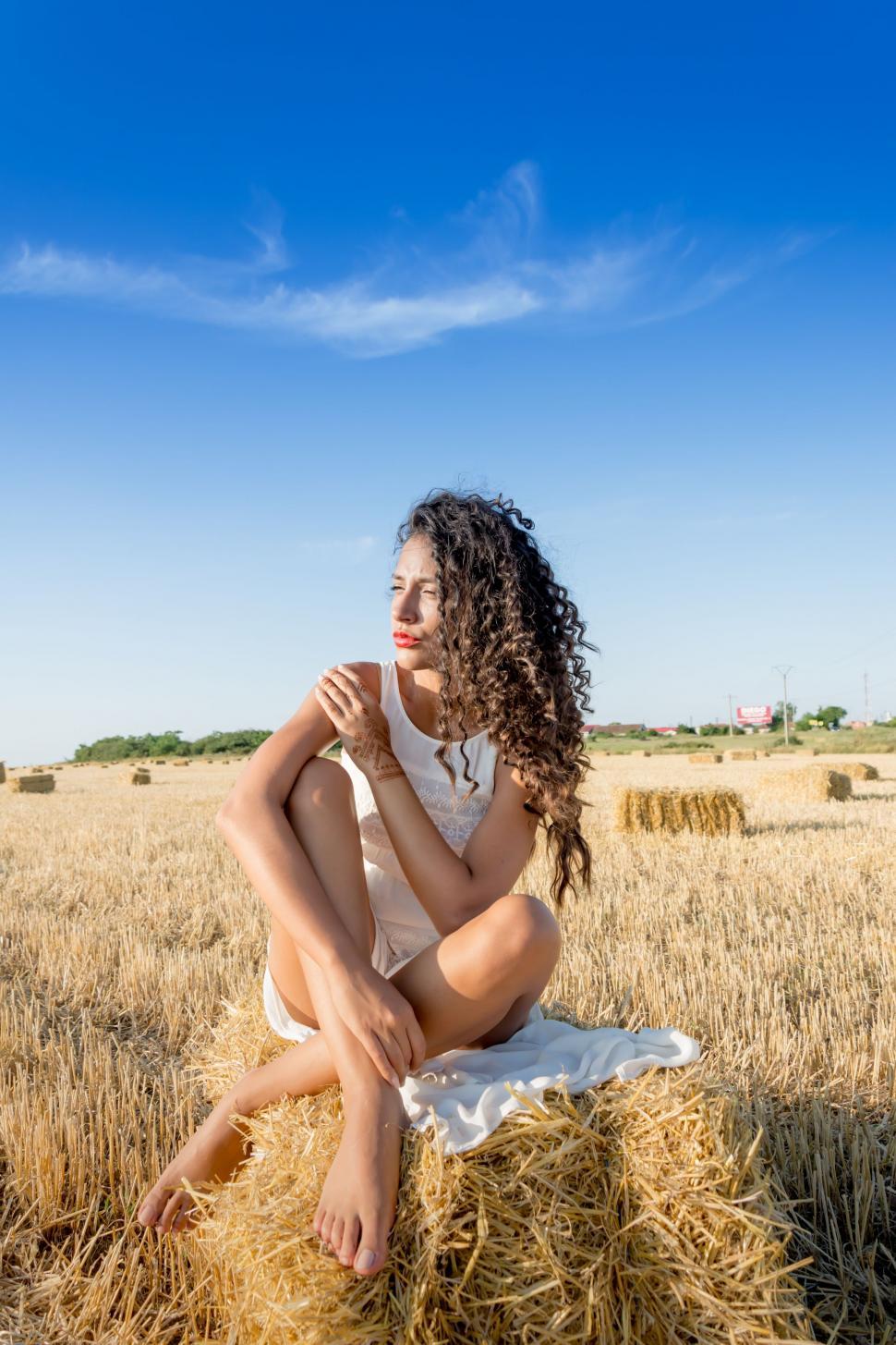 Free Image of Woman Sitting on Top of a Pile of Hay 