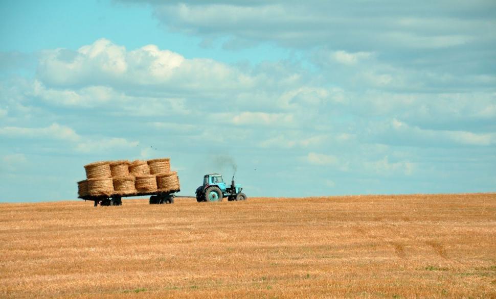 Free Image of Tractor Pulling Hay Trailer Across Field 