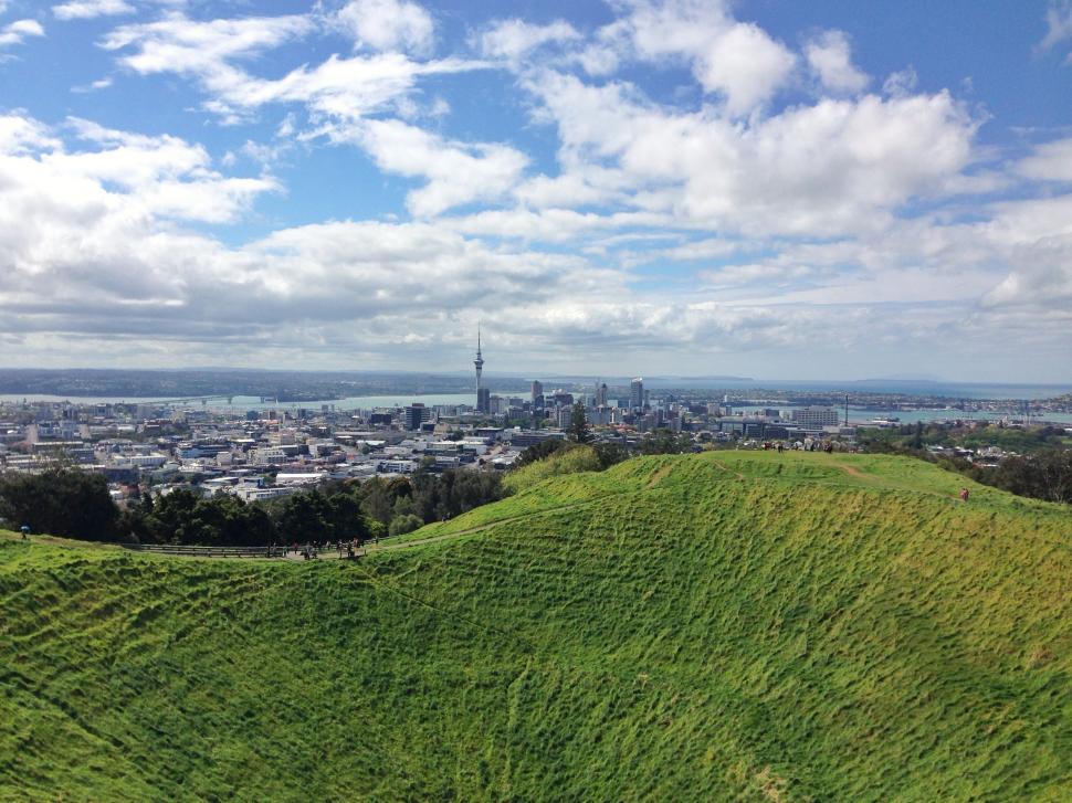 Free Image of Grassy Hill Overlooking City in the Distance 