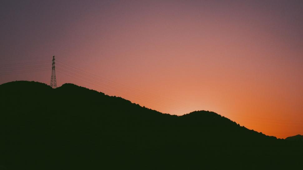 Free Image of Sun Setting Over Hill With Radio Tower 