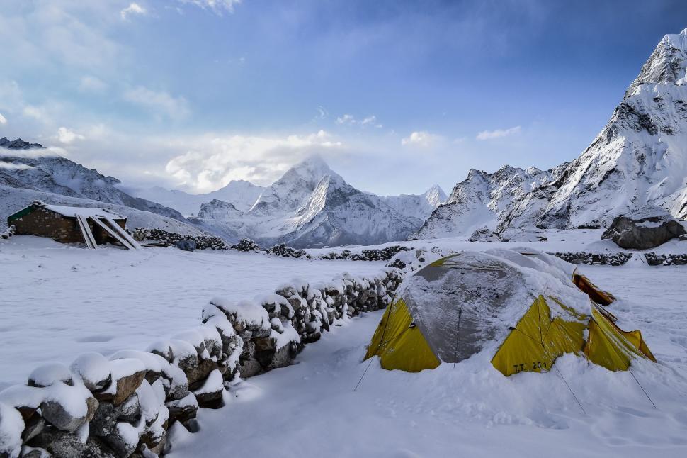 Free Image of Tent Pitched in Snow Next to Stone Wall 