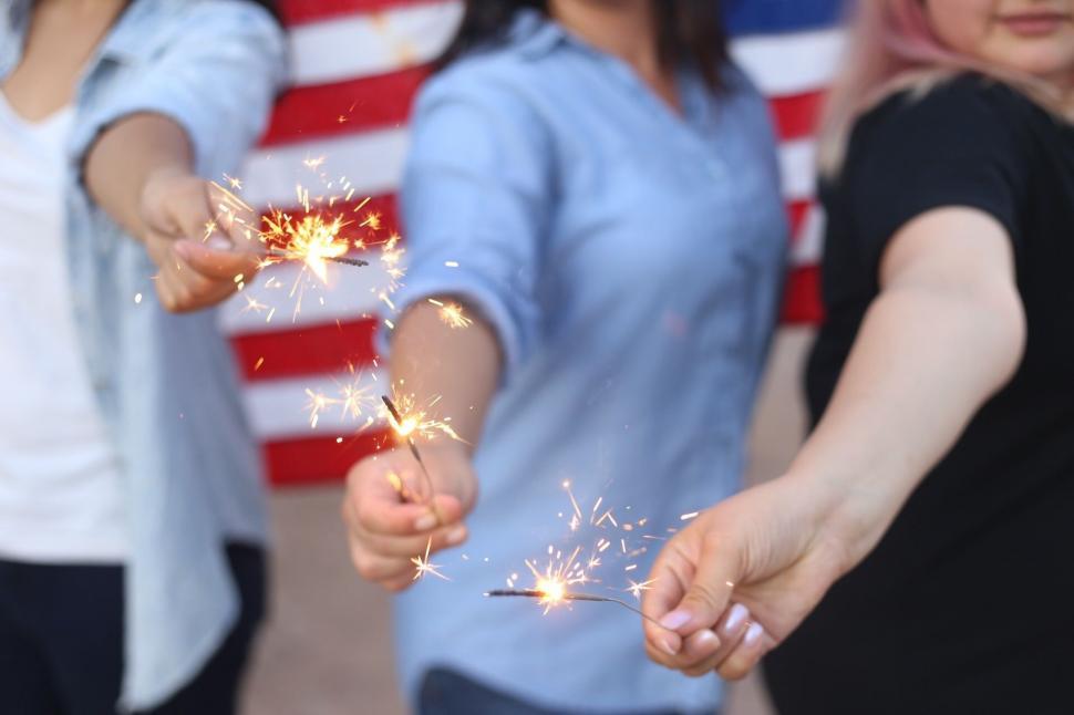 Free Image of Two Women Holding Sparklers in Front of an American Flag 