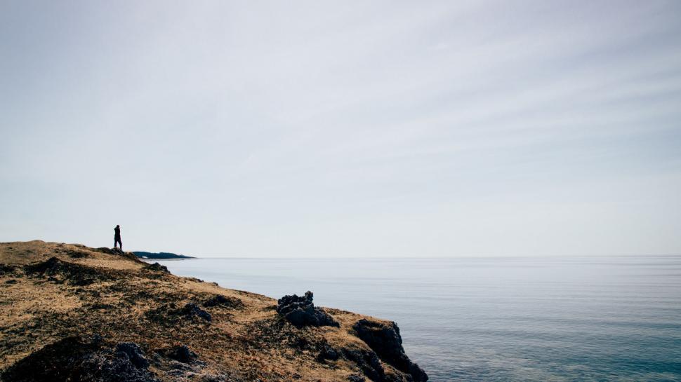 Free Image of Man Standing on Cliff by Ocean 