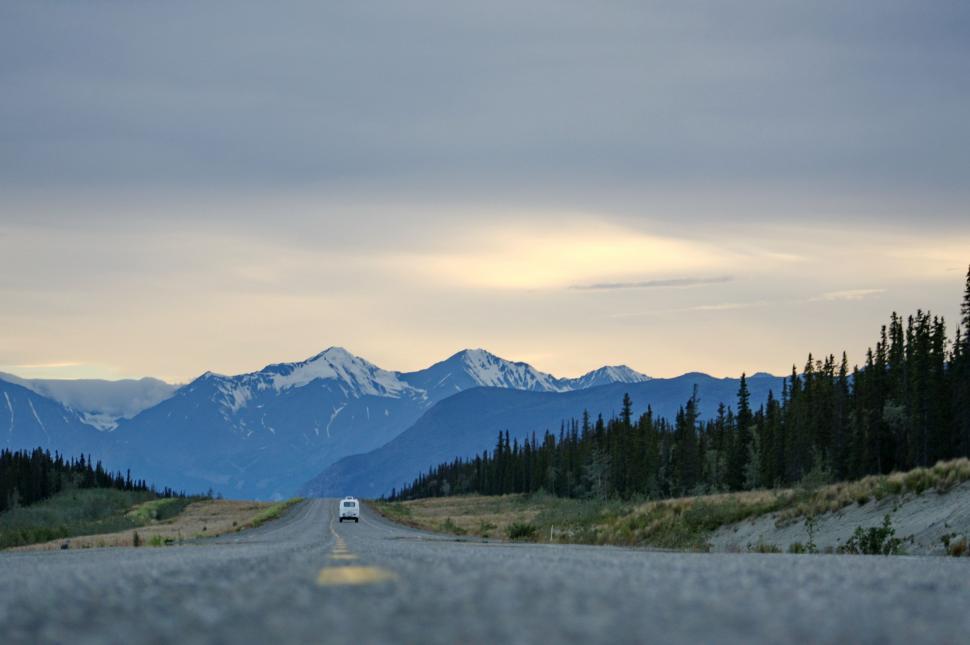 Free Image of Car Driving Down Road With Mountains in Background 