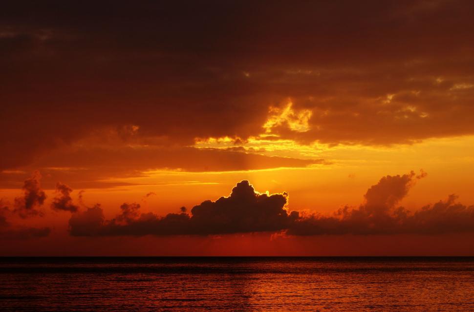 Free Image of Sun Setting Over Ocean With Clouds 