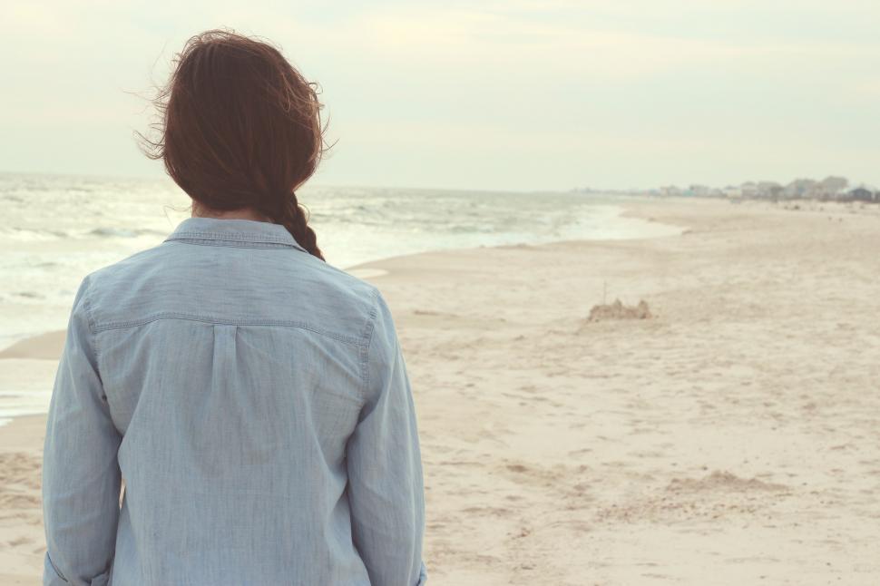 Free Image of Woman Standing on Beach Looking at Ocean 